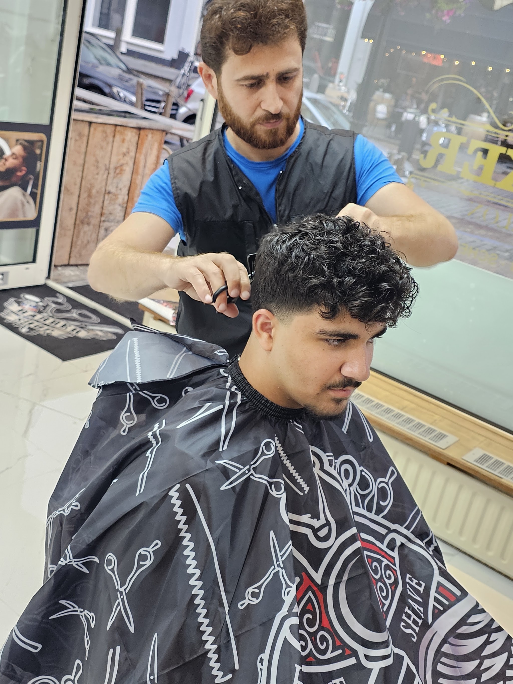 De barbier knipt een klant met krullen, van dichtbij