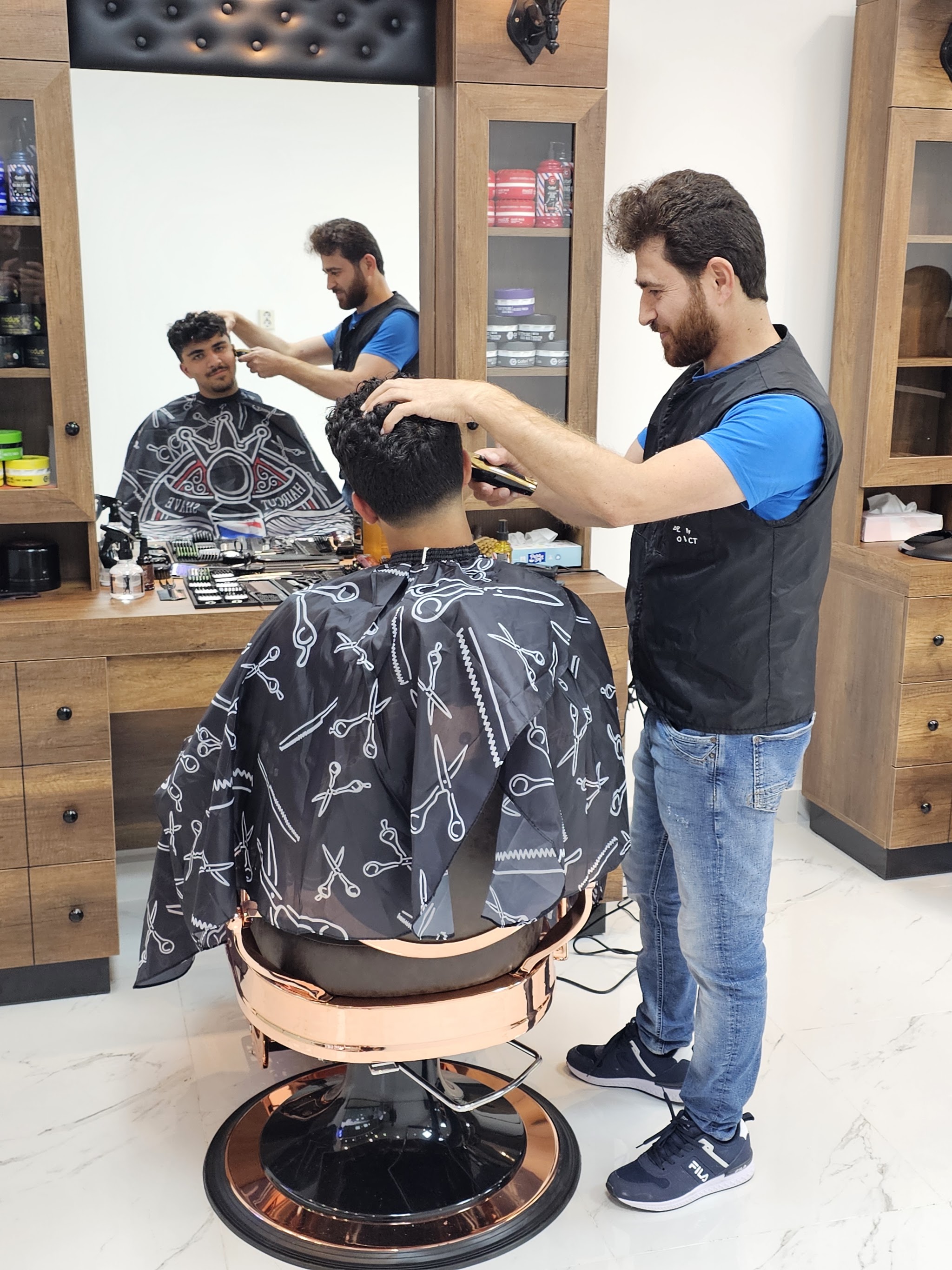 De barbier brengt het haar van een klant in model, achter hem een tweede stoel